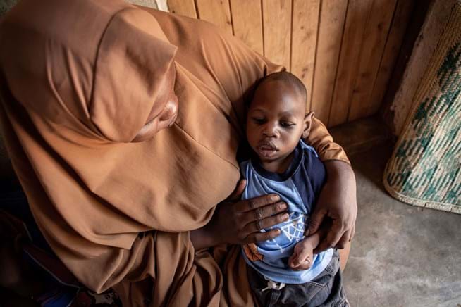 A woman wearing a headscarf with a little boy in her arms