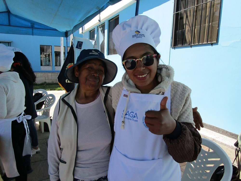 Two women standing outside one in a chef's hat and sunglasses giving a thumbs up
