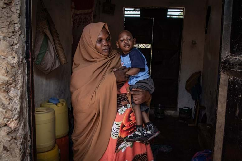 A woman wearing a headscarf holding a yong child