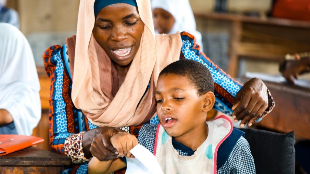 A woman helping a yong person in class