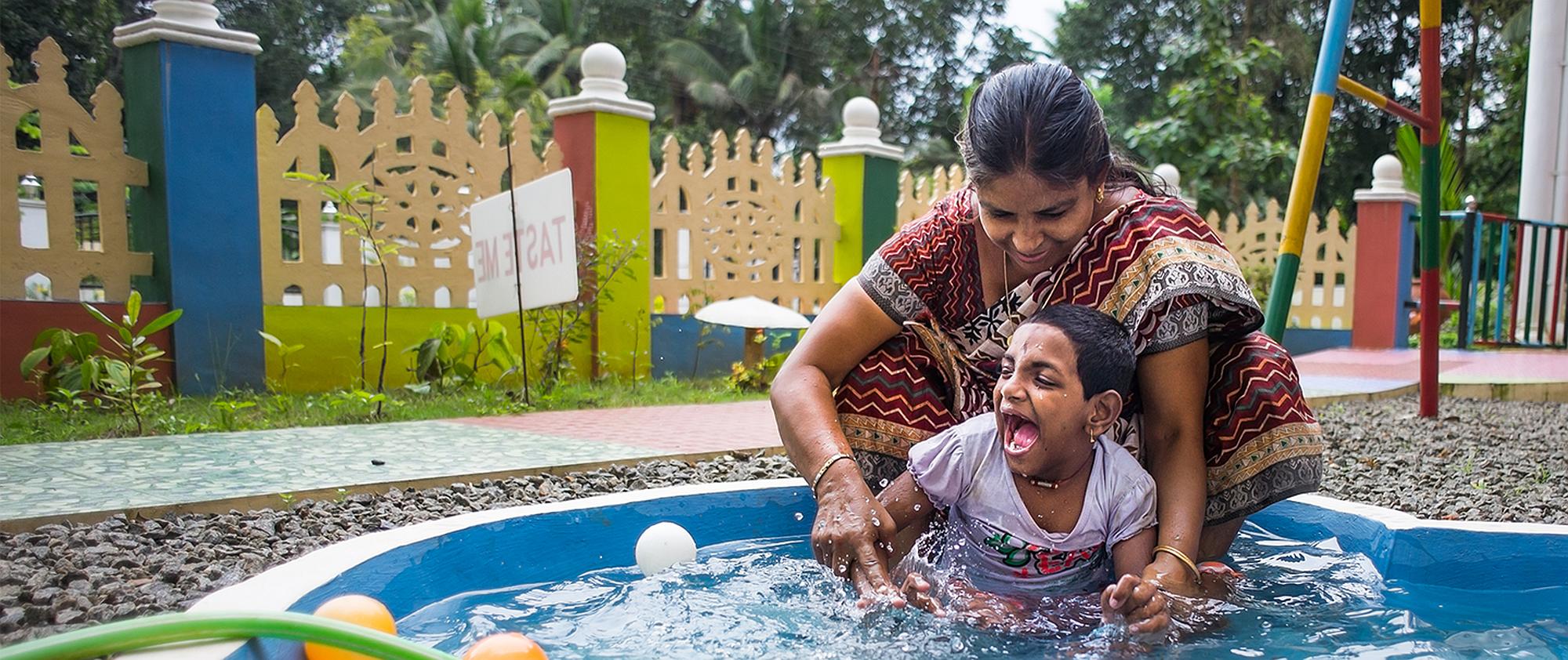 A woman spashing with a young person in a pool