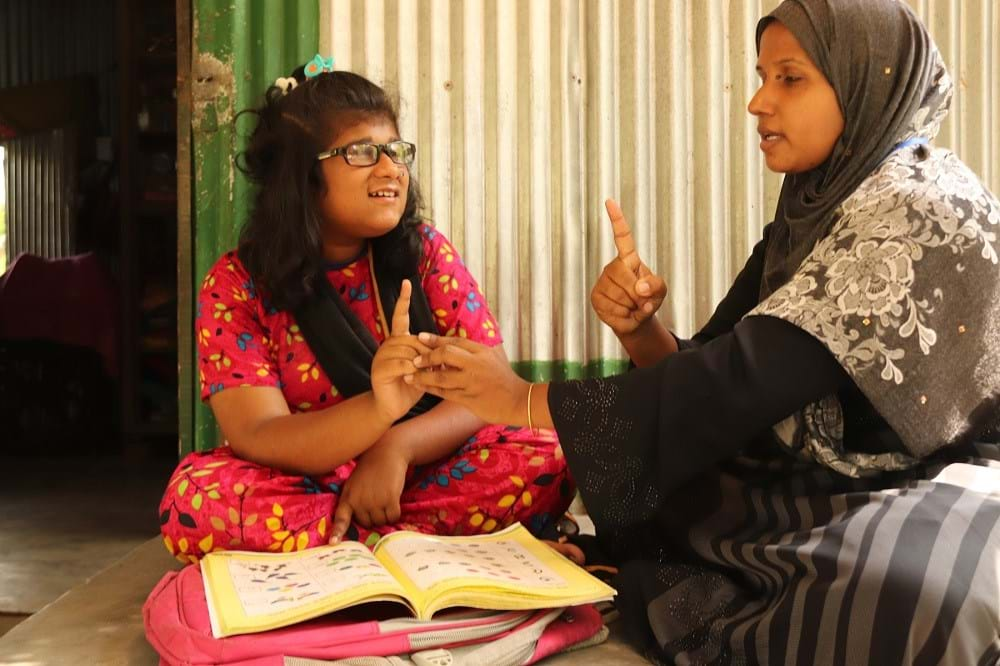 A woman teaching a young woman how to sign