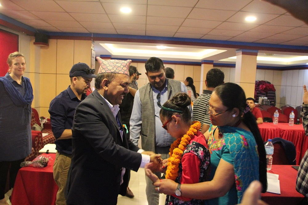 A man shaking the hand of a young girl who is with her carer