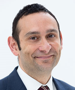 A potrait of a man wearing a suit and tie smiling at the camera