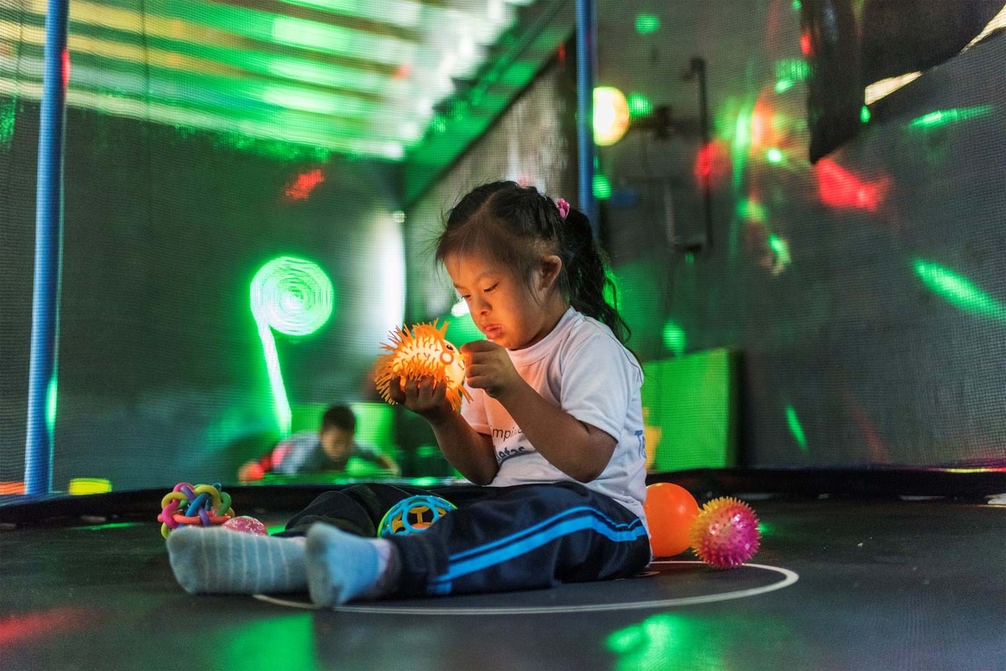 a little girl in a sensory room, holding a light up toy