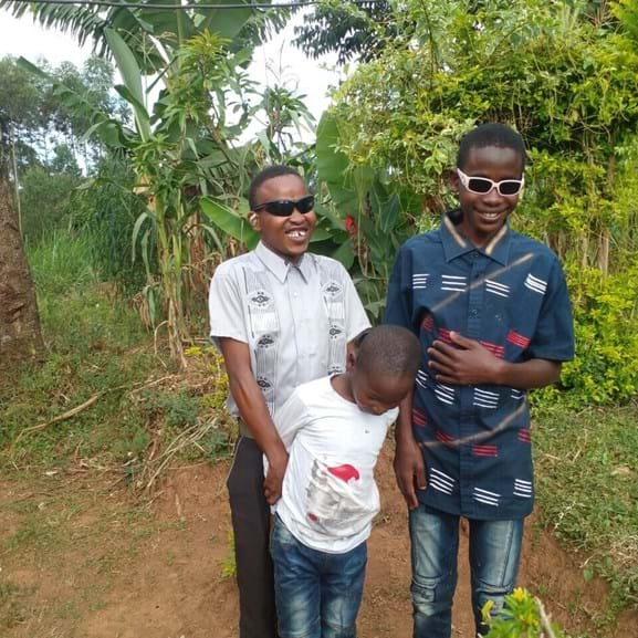 Three young boys standing next to trees