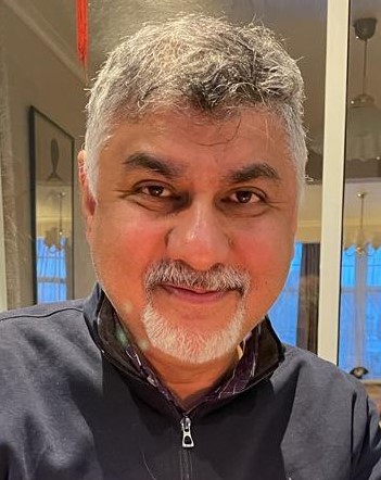 A man with silver hair and beard smiling at thr camera