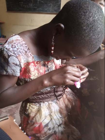 A girl stares closely at the bag she is crafting