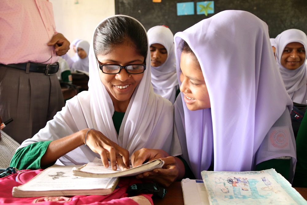 A young woman smiles as she reads a book with her fingers