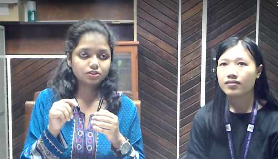 A young woman sitting with her interpreter who is also a woman.