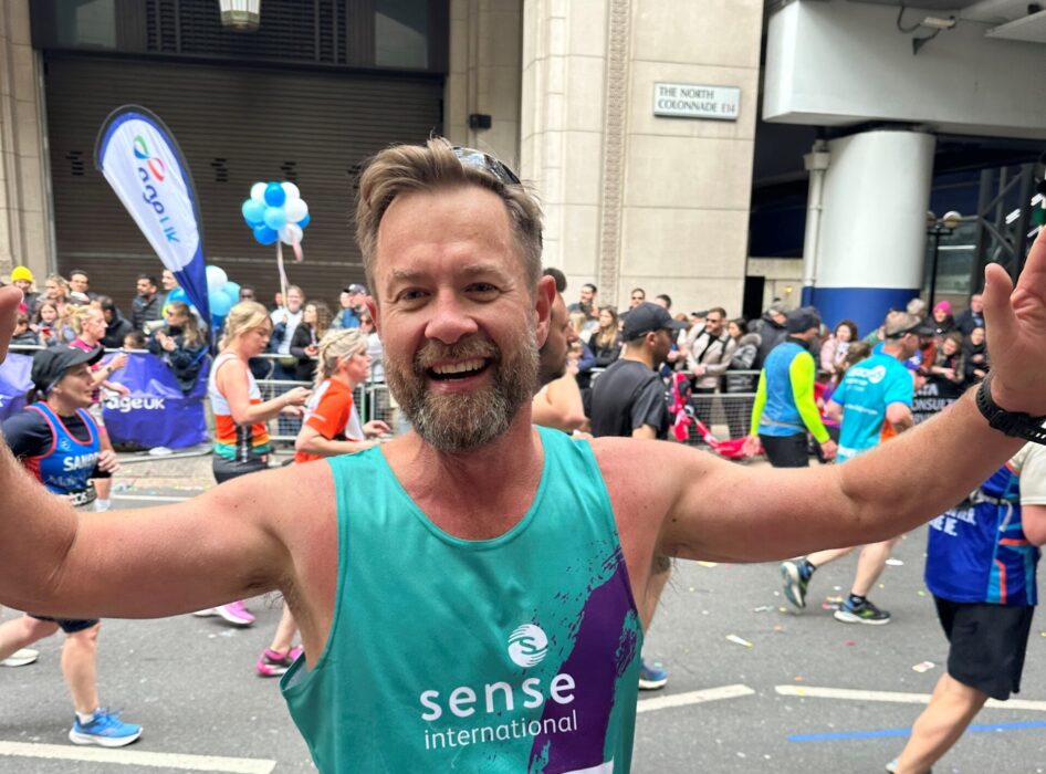 A man running the London Marathon wearing a Sense International branded vest.