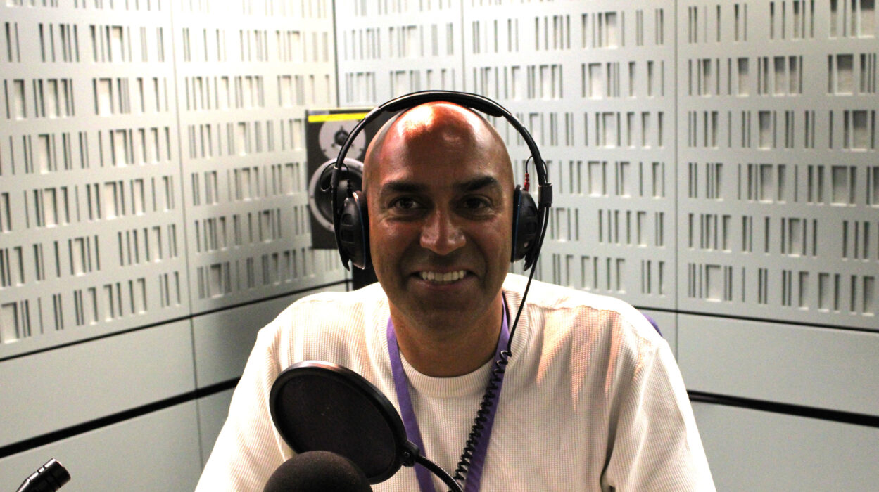 Amar Latif sits ready to do his voiceover at Radio 4. He sits behind a large microphone