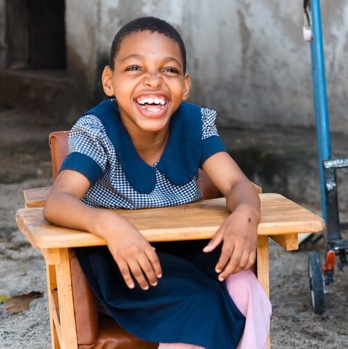 A child smiles behind their school desk