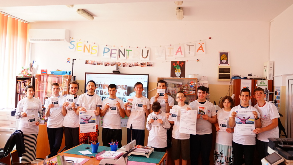 A classroom full of schoolchildren in Romania hold up colourful artwork they've created