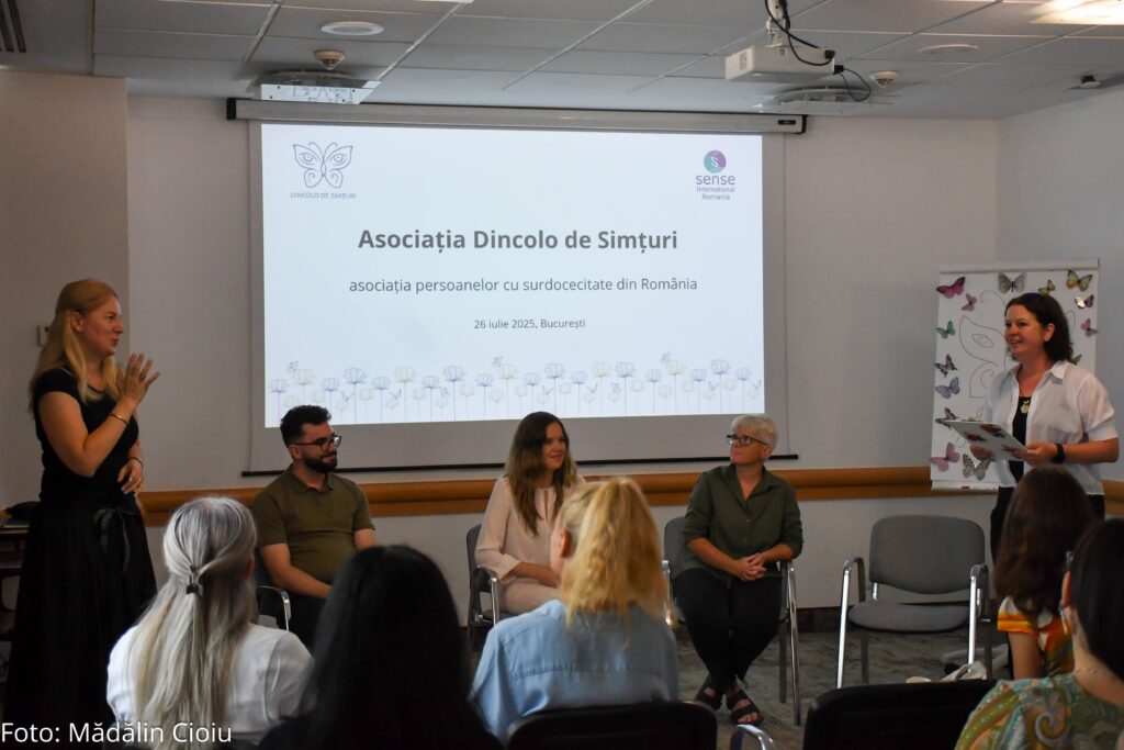 A projector screen with text written in Romanian (translation: The Association Beyond Senses). Five young people are gathered around.