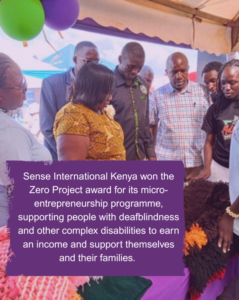 A group of Kenyan adults gather around a market stall. Text reads: Sense International Kenya won the Zero Project award for its micro-entrepreneurship programme, supporting people with deafblindness and other complex disabilities to earn an income and support themselves and their families. 