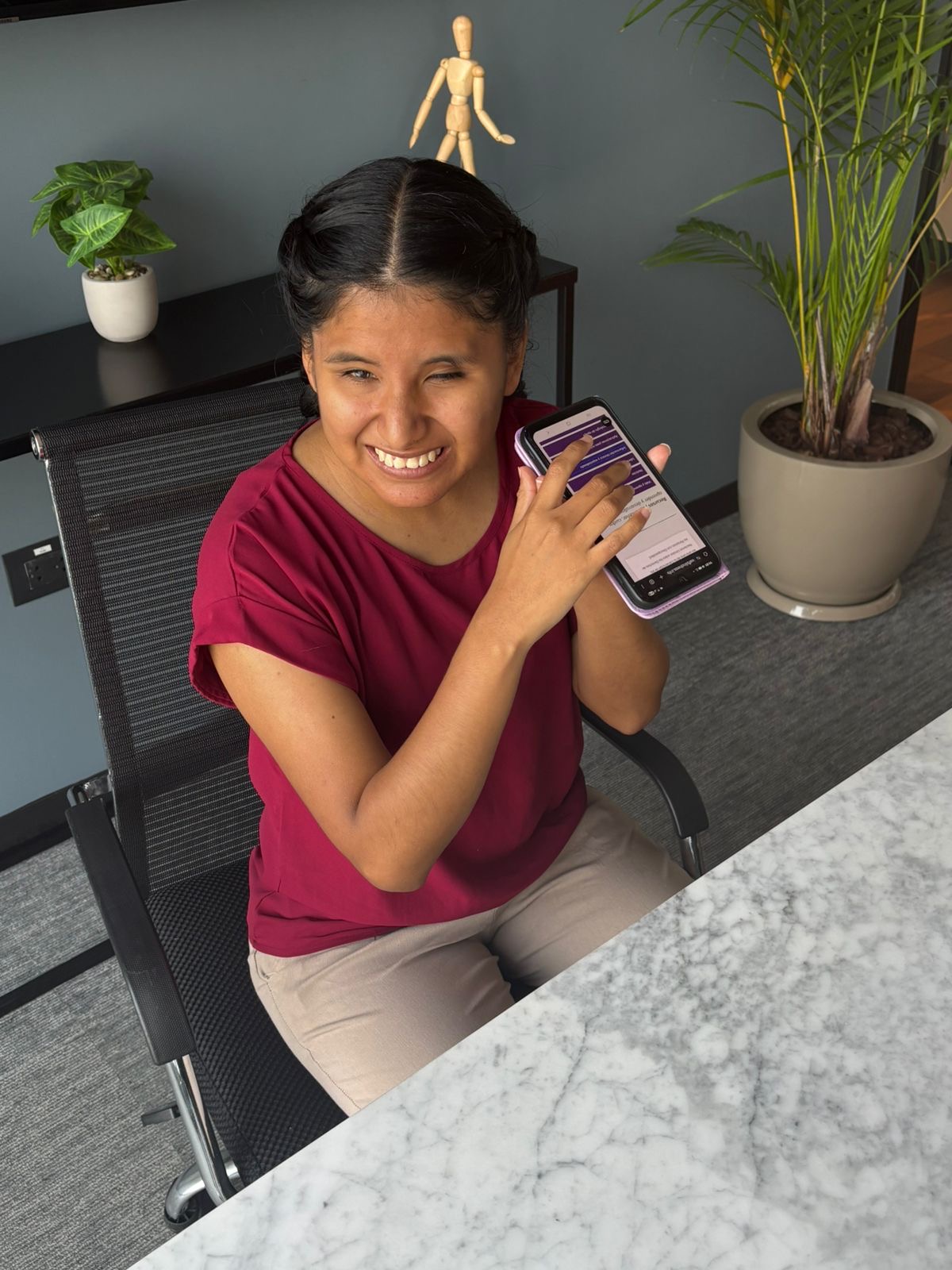 A young Peruvian woman with partial blindness wearing her hair in braids demonstrates the Hub on her phone.