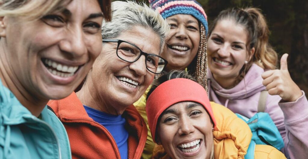 A group of smiling women in colourful hiking gear pose for a selfie