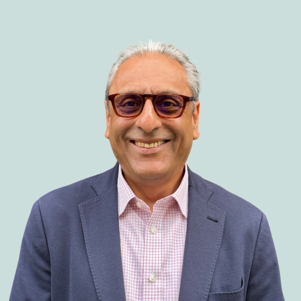 Headshot of a South Asian gentleman with white hair wearing glasses