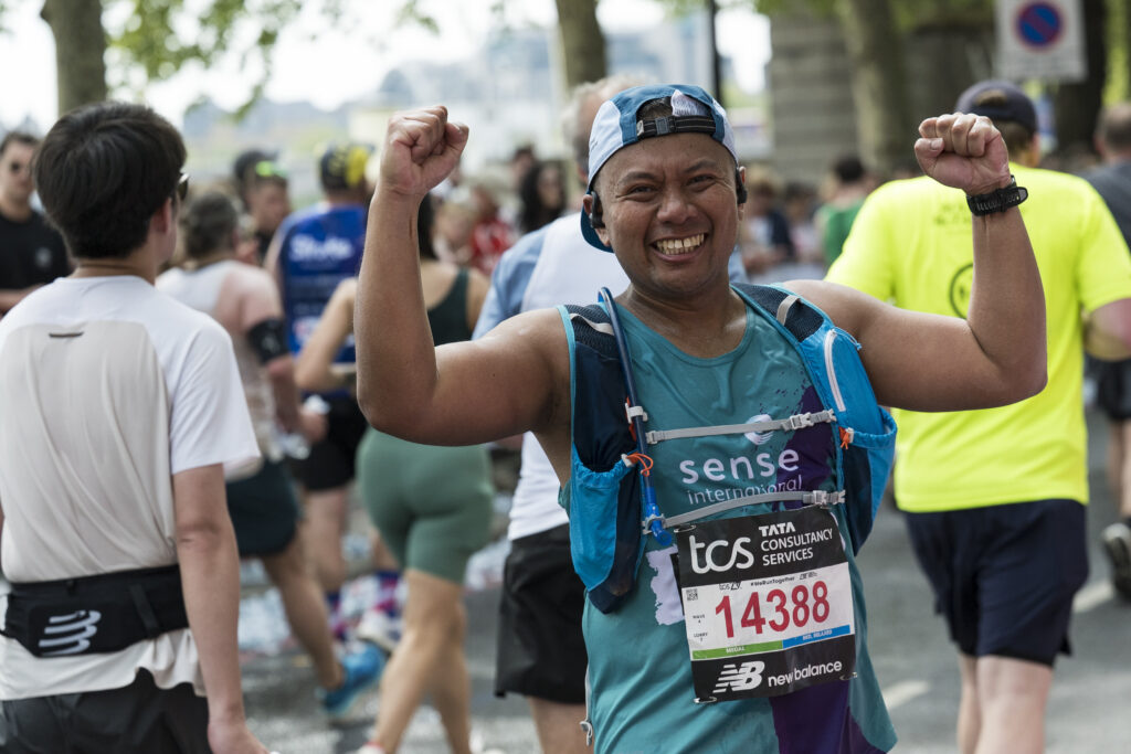 A man in a Sense International running vest cheering