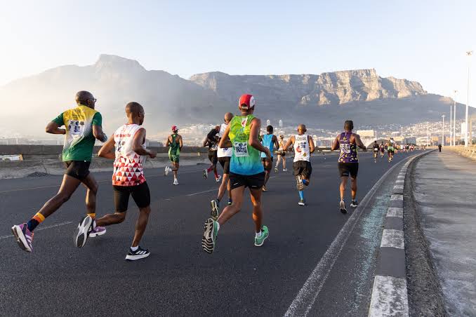 A group of marathon runners against the backdrop of misty mountains